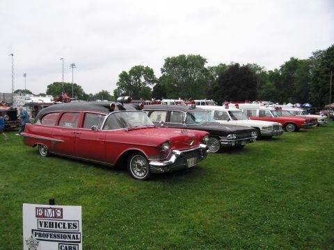 1991 Ford Crown Victoria - A collection of vintage emergency and professional vehicles are displayed on a grassy field under an overcast sky.