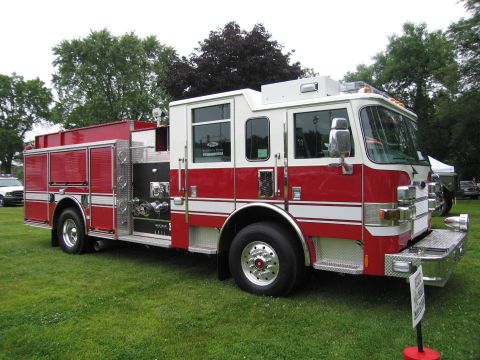 1991 Ford Crown Victoria - A red and white fire truck is parked on a grassy field with trees in the background.
