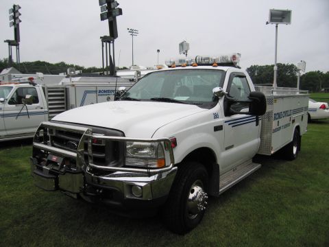 1991 Ford Crown Victoria - White Ford F-series truck with utility bed and emergency lights parked on grass.