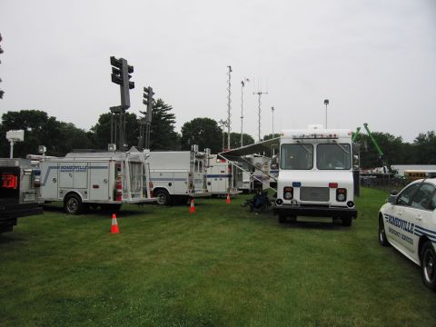 1991 Ford Crown Victoria - A fleet of emergency service vehicles, including trucks with traffic signal equipment, are parked on a grassy field.