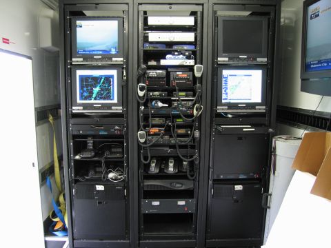 1991 Ford Crown Victoria - This image shows the interior of a mobile command center, filled with various electronic equipment including monitors, radios, and telephon…