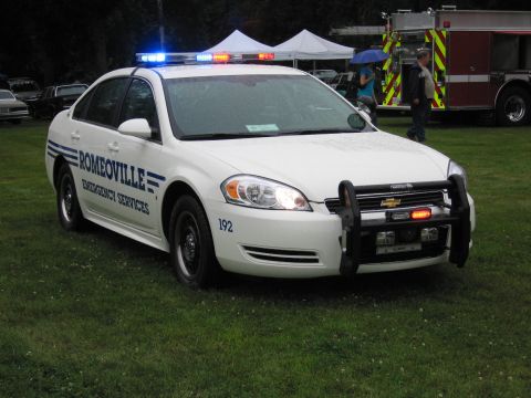 1991 Ford Crown Victoria - A Romeoville police car with emergency lights illuminated sits on a grassy field.