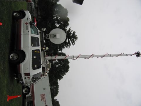 1991 Ford Crown Victoria - A white van equipped with a satellite dish and antenna is parked outdoors, with another vehicle visible in the background.