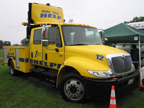 1991 Ford Crown Victoria - A bright yellow truck with emergency markings is parked on grass, with tents in the background.