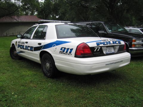 1991 Ford Crown Victoria - A North Aurora police car is parked on grass, with another vehicle visible behind it.