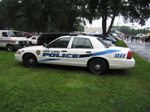 1991 Ford Crown Victoria - Side view of a North Aurora police car with blue stripe and "POLICE" text.
