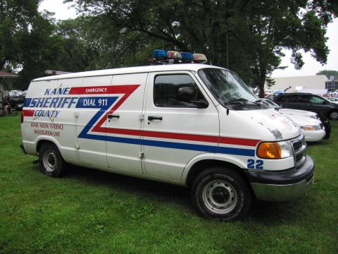 1991 Ford Crown Victoria - A white van marked for the Kane County Sheriff's Bomb/Arson Evidence Investigation Unit is parked on grass.