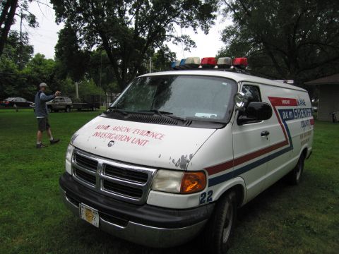 1991 Ford Crown Victoria - A white van, marked as an Arson/Evidence Investigation Unit, is parked on a grassy area with trees in the background.