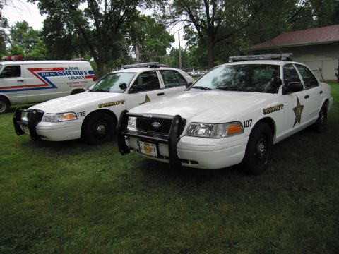 1991 Ford Crown Victoria - Two Ford Crown Victoria police cruisers and a sheriff van are parked on a grassy area.