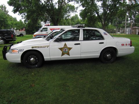 1991 Ford Crown Victoria - A sheriff's department vehicle is parked on a grassy area with trees in the background.