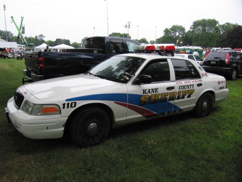 1991 Ford Crown Victoria - A Kane County Sheriff's patrol car is parked on the grass, with a pickup truck and other vehicles in the background.