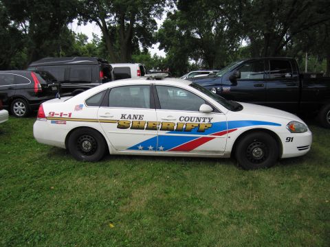 1991 Ford Crown Victoria - Side view of a Kane County Sheriff's patrol car with police lights on the roof.