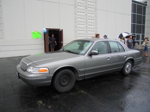 1991 Ford Crown Victoria - A 1991 Ford Crown Victoria sedan is parked outside a building on a rainy day.