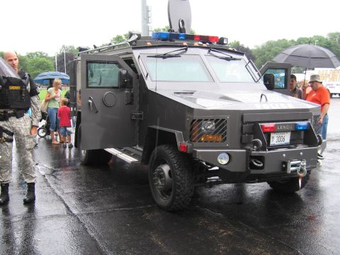 1991 Ford Crown Victoria - An armored tactical vehicle, possibly a Lenco, is parked on a wet surface with people nearby.