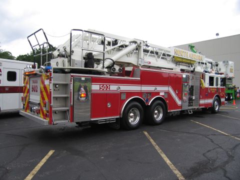 1991 Ford Crown Victoria - A red fire truck with a large ladder is parked next to an ambulance.