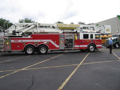 1991 Ford Crown Victoria - Side view of a North Aurora fire truck with its ladder extended, parked in a lot.