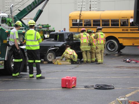 1991 Ford Crown Victoria - Firefighters and a tow truck are involved in an operation with a black sedan and a yellow school bus.