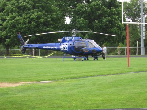 1991 Ford Crown Victoria - A blue helicopter with identification markings sits on a grassy field, possibly a sports field.
