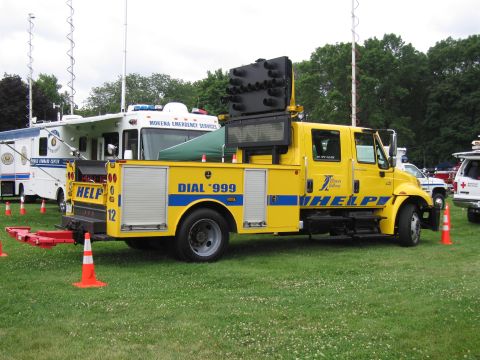 1991 Ford Crown Victoria - A yellow truck equipped with traffic control lights and a digital message board is parked on a grassy field.