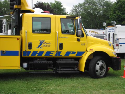 1991 Ford Crown Victoria - A yellow truck with 'Illinois Tollway HELP' written on its side is parked on a grassy area.