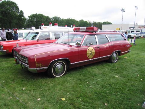 1991 Ford Crown Victoria - A red 1969 station wagon, possibly a Ford, is parked on grass next to an ambulance and other vehicles.