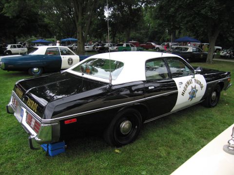 1991 Ford Crown Victoria - A vintage highway patrol car is parked on the grass at an outdoor event with other vehicles in the background.