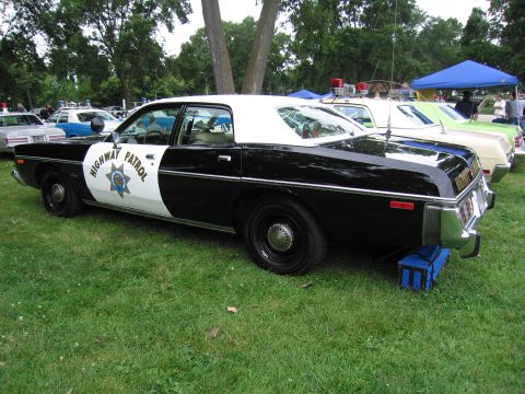 1991 Ford Crown Victoria - A vintage police car is parked on a grassy lawn next to other vehicles.