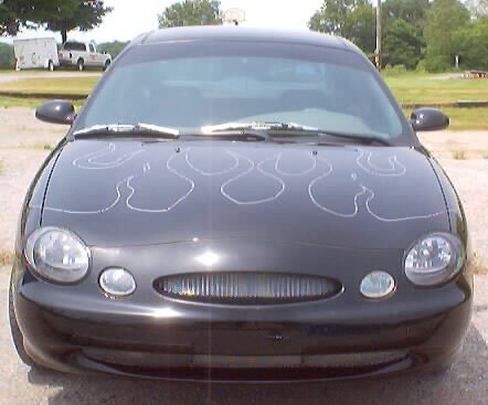 1999 Ford Taurus - This black sedan features flame decals on its hood and a distinctive vertical slat grille.