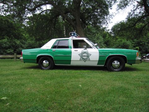 1991 Ford Crown Victoria - This police car has a two-tone green and white paint scheme with a sheriff's department star emblem.