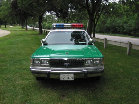 1991 Ford Crown Victoria - This green police car, seen from the front, has a light bar and a California license plate.
