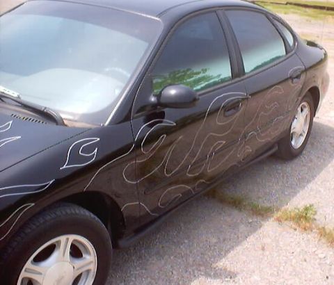 1999 Ford Taurus - A black 1999 Ford Taurus sedan is shown with custom white flame decals on its side.