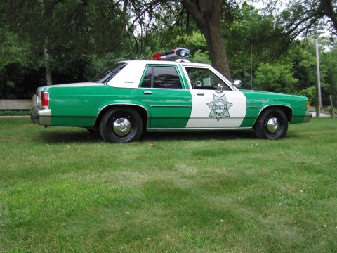 1991 Ford Crown Victoria - This 1991 Ford Crown Victoria police car features a distinctive green and white livery with a sheriff's star emblem on the door.
