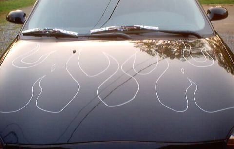 1999 Ford Taurus - Glossy black hood of a car detailed with white ghost-flame pinstripe outlines, windshield wipers and mirrors visible.