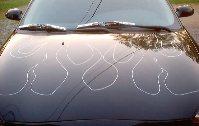 Black car hood with white ghost-flame pinstripe outline reflecting sky