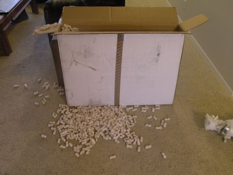 1998 Subaru Legacy - Packing peanuts have spilled out of an open cardboard box onto the carpeted floor.