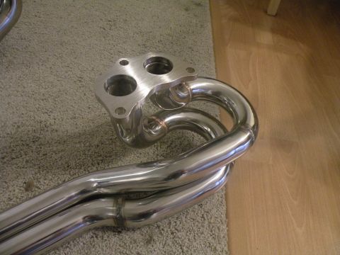 1998 Subaru Legacy - A close-up view of a polished stainless steel exhaust manifold, a two-bolt flange and curved pipes.