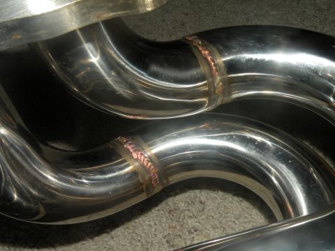 1998 Subaru Legacy - Shiny exhaust pipes with copper-colored welds are shown in a close-up view.