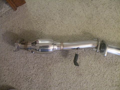 1998 Subaru Legacy - A shiny exhaust pipe part is shown on a carpeted floor, with no visible year or vehicle identification.