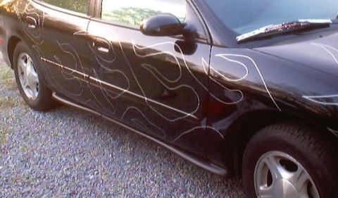 1999 Ford Taurus - Side view of a black 1999 Ford Taurus with custom flame graphics.