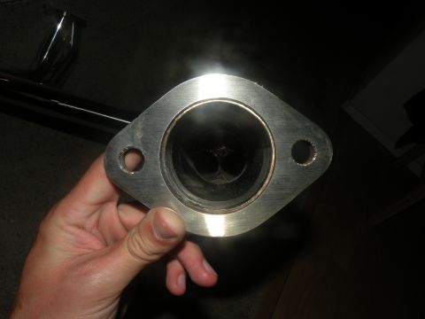 1998 Subaru Legacy - A close-up view of a metal exhaust pipe flange held by a person's hand.