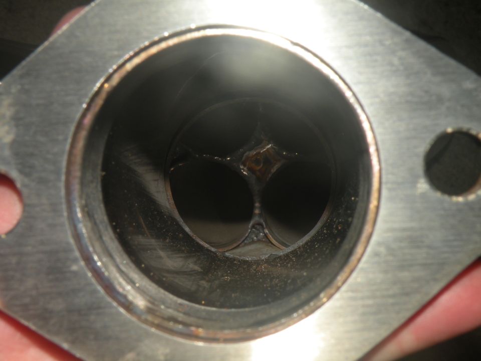 Exhaust valve with carbon buildup and slight damage, viewed from the intake side
