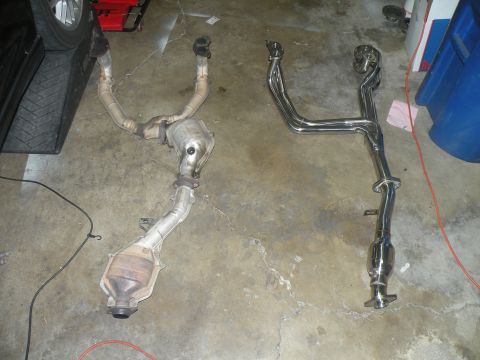 1998 Subaru Legacy - Two different exhaust systems are shown on the floor, one appears to be a stock catalytic converter assembly and the other a performance ex…