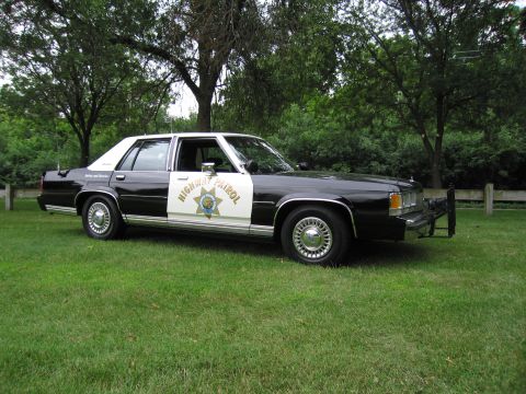 1991 Ford Crown Victoria - This Ford Crown Victoria is marked as a Highway Patrol vehicle and is parked on a grassy area with trees in the background.