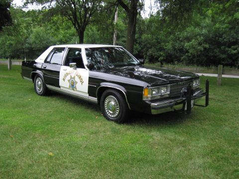 1991 Ford Crown Victoria - This 1991 Ford Crown Victoria police car is parked on a grassy area with trees in the background.