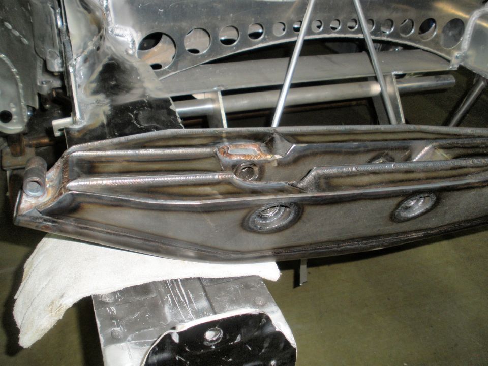 Close-up of welded metal suspension part on a stand, with a white cloth underneath