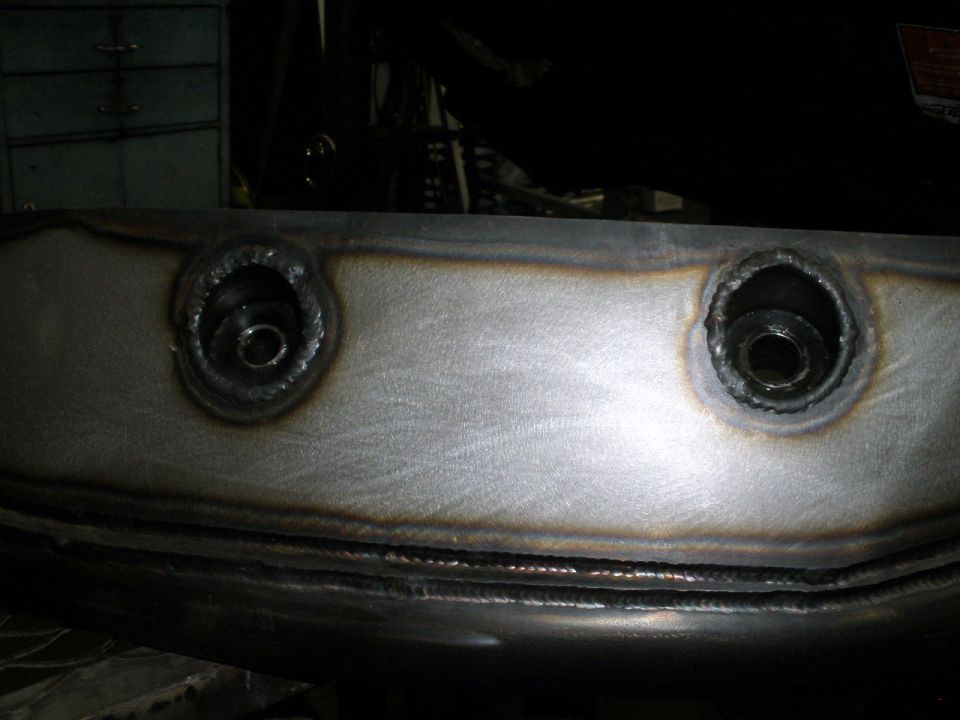 Welded metal part with two bolt holes, showing weld marks and metal sheen