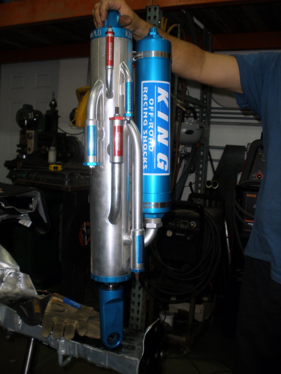 Two King Off-Road Racing Shocks, one silver and one blue, held by a person