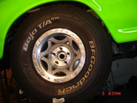 1995 Ford Bronco - Close-up of a BFGoodrich Baja T/A tire mounted on a multi-spoke wheel, attached to a vehicle with bright green bodywork.