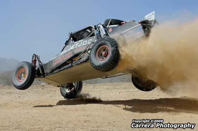 Off-road buggy mid-air, kicking up dust. Number 507 visible