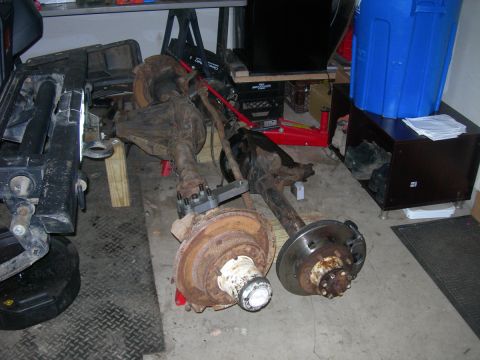 1991 Jeep Wrangler - Two vehicle axles, likely for a Jeep Wrangler, are shown disassembled in a garage setting.
